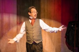 Picure of storyteller, Chris Connaughton, performing in front of a bright coloured backdrop