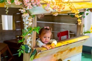 A little girl peeping out of the Fairytale Forest house