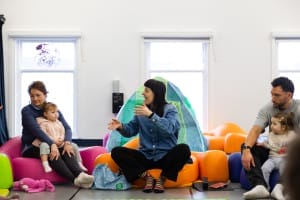 Artist Bridie jackson sitting on the floor interacting with adults and babies.