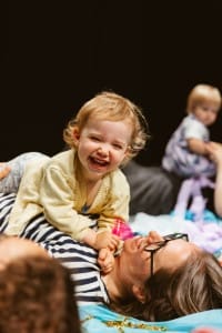 Toddler laughing and cuddling their mum laying down on the floor during the After Party show
