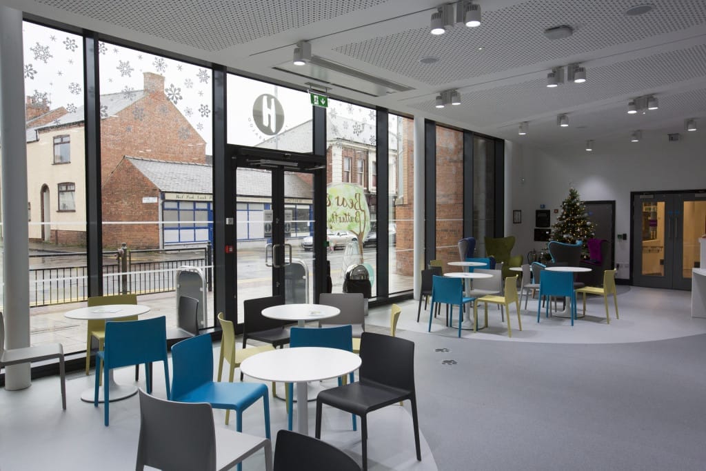 A view inside The Hullabaloo café looking towards the full length windows. Set of tables and chair as well as a Christmas tree in the corner. 