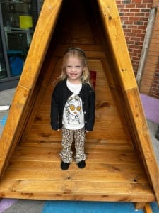 Little girl smiles at the camera from inside new play hut