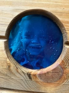 Little girl peeks through a blue window in a new play hut