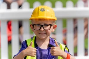 Little boy wearing glasses, a yellow hard hat and high visibility vest
