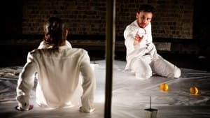 2 actors on stage divided by a paper wall